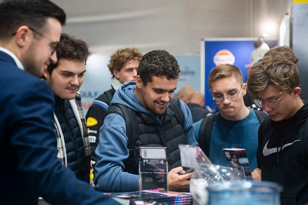 A group watches a demonstration around a display.