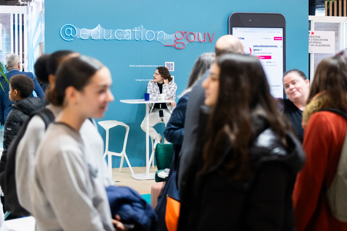 Visitors talk in front of the French education ministry stand.