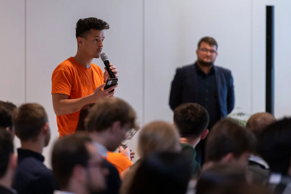 A young speaker holding a microphone among the attendees.