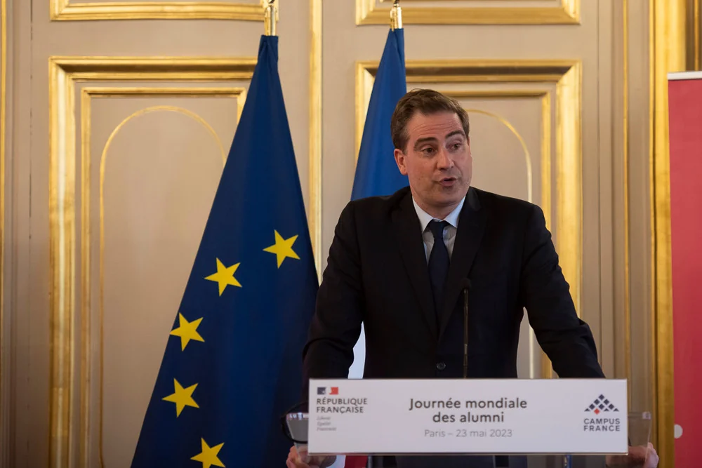 A speaker at a lectern in front of the French and European flags.