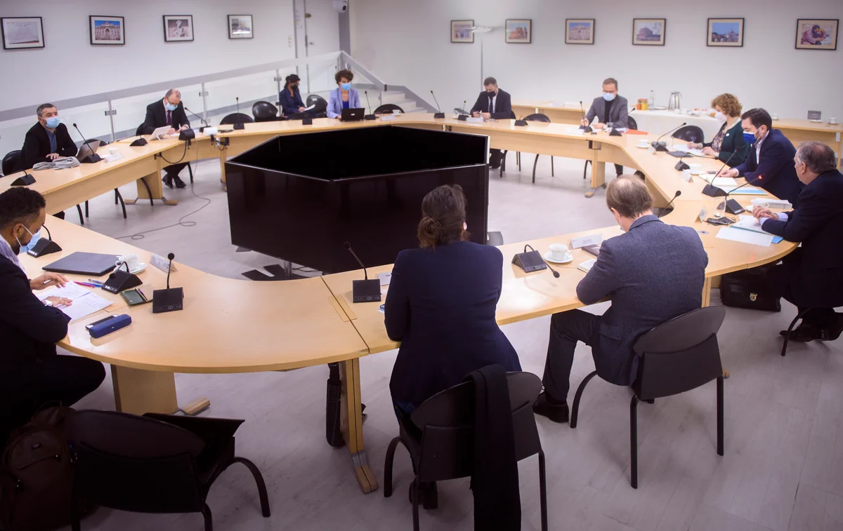 A meeting around a large oval table.