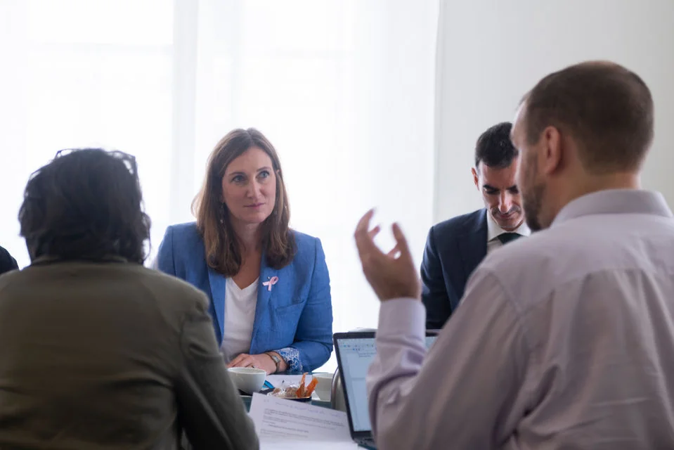 Four people talk around a small table.