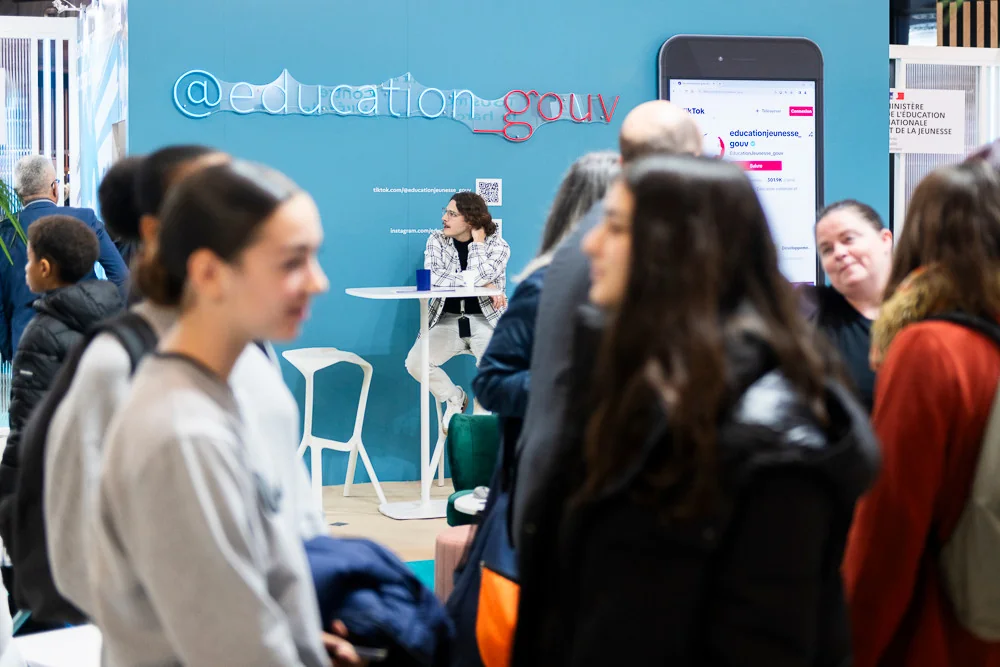 Visitors talk in front of the French education ministry stand.