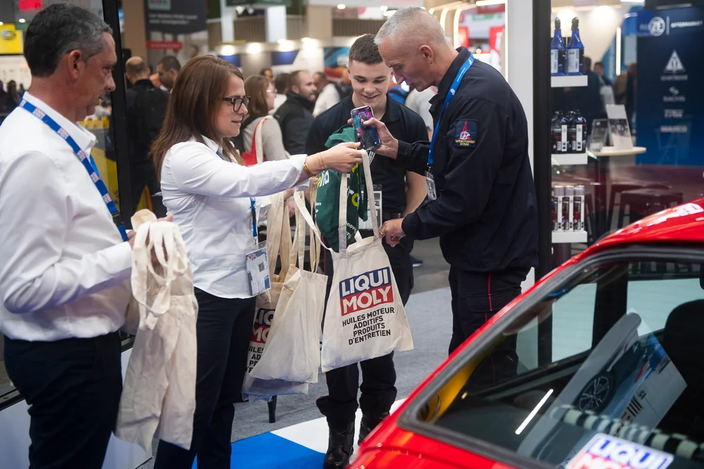 Visitors and the LIQUI MOLY team talk beside a red car.