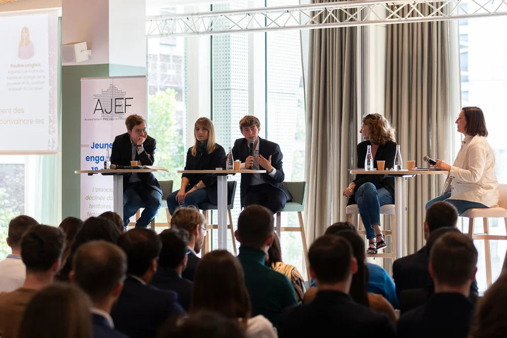 A panel discussion and its audience in a bright room.