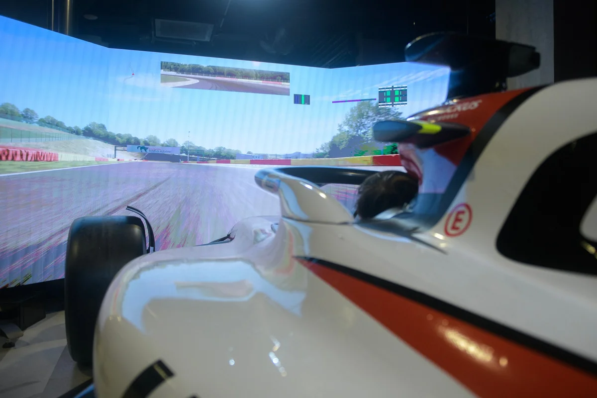 A simulator cockpit in front of a motor-racing screen.