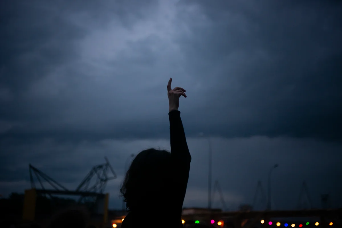 A woman raising a finger towards a dark, threatening sky