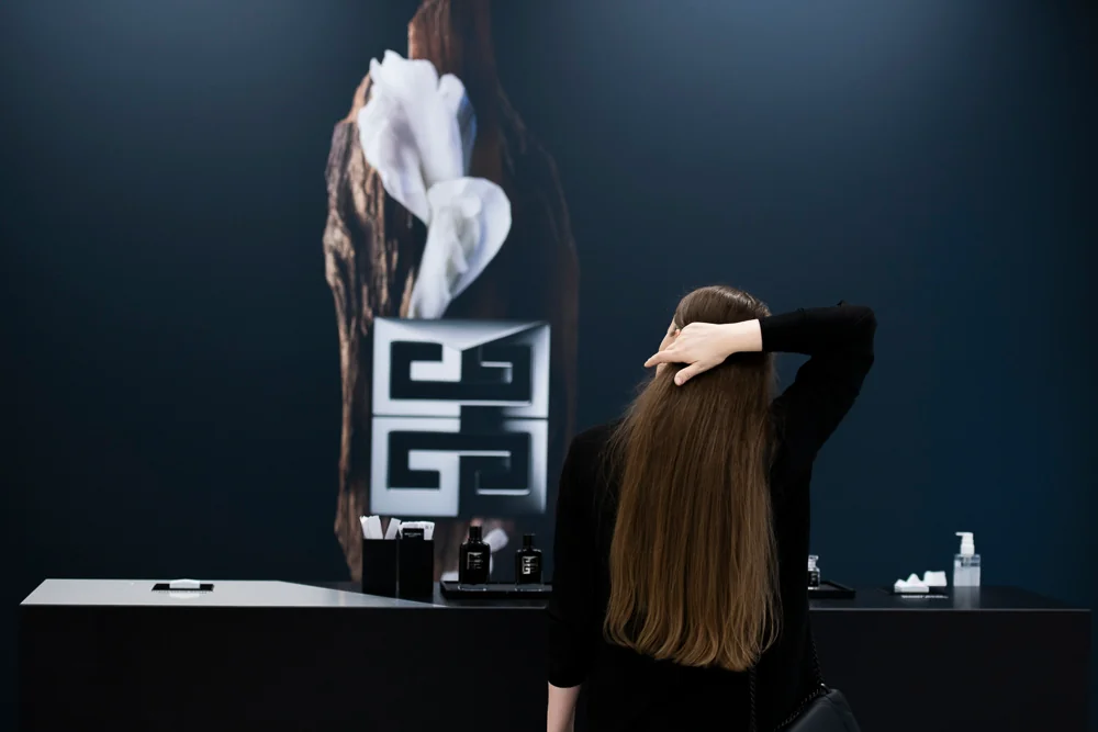 A guest in front of a Givenchy display and fragrance bottles.