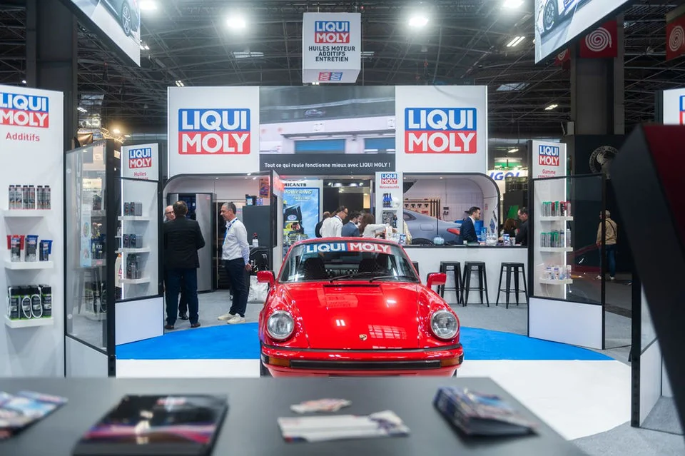 Visitors and the LIQUI MOLY team around a red car at the stand.